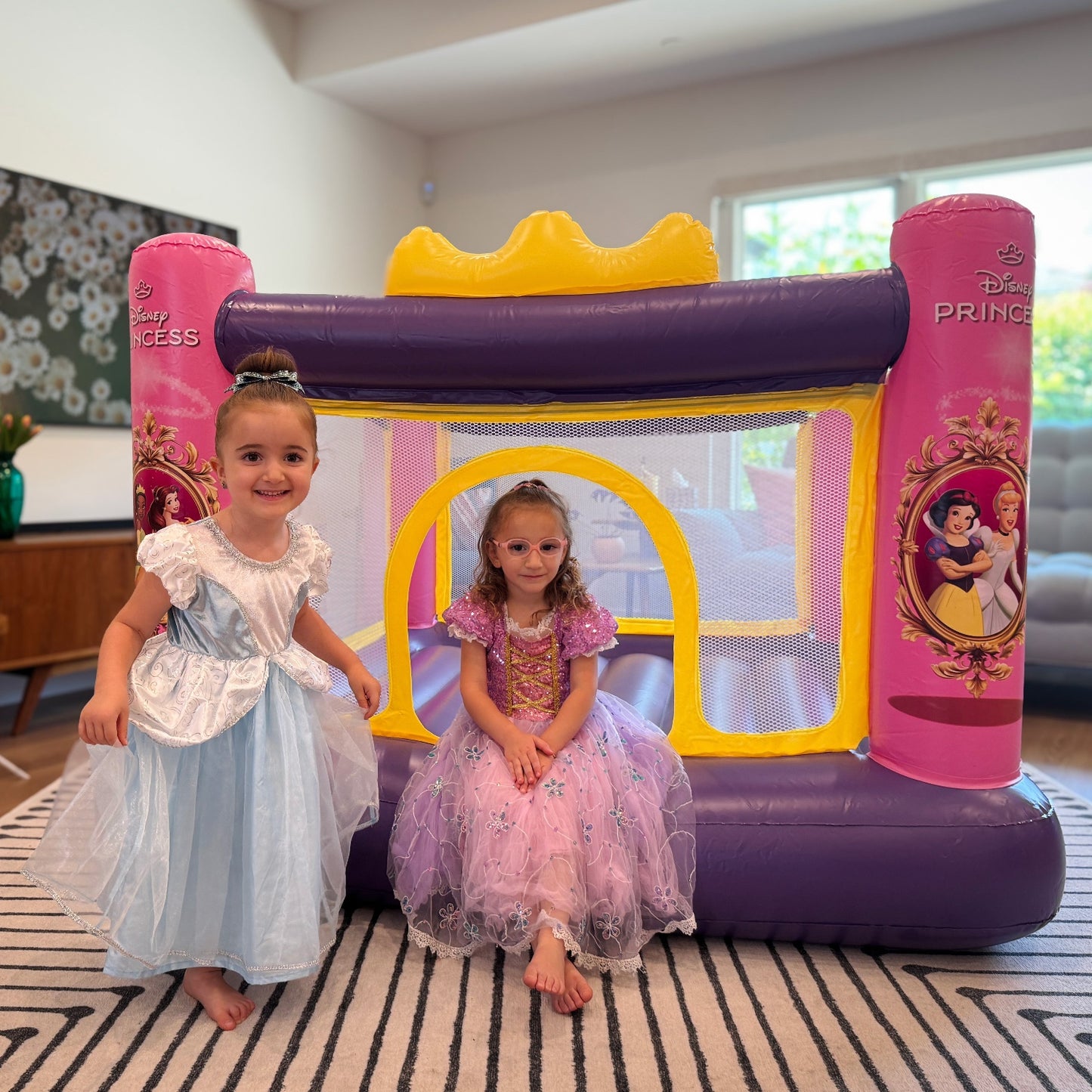 Children smiling while standing in front of the Disney Princess Inflatable Bounce House