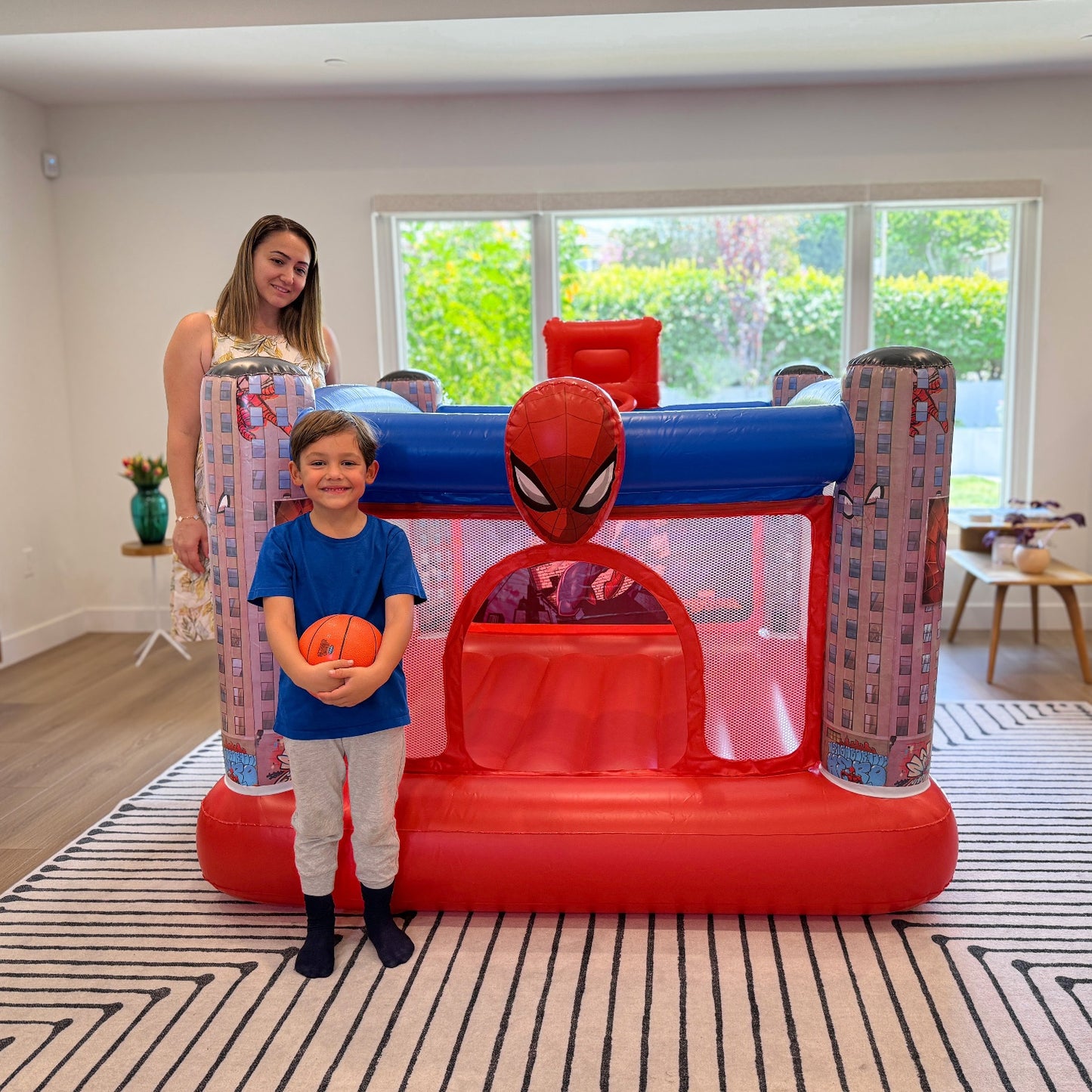 Mom and kid standing beside the Spider-Man Inflatable Bounce House